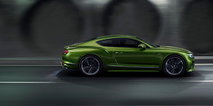  Bentley Surrey Bentley Continental GT coupe in Tourmaline Green paint driving in profile on a dark road