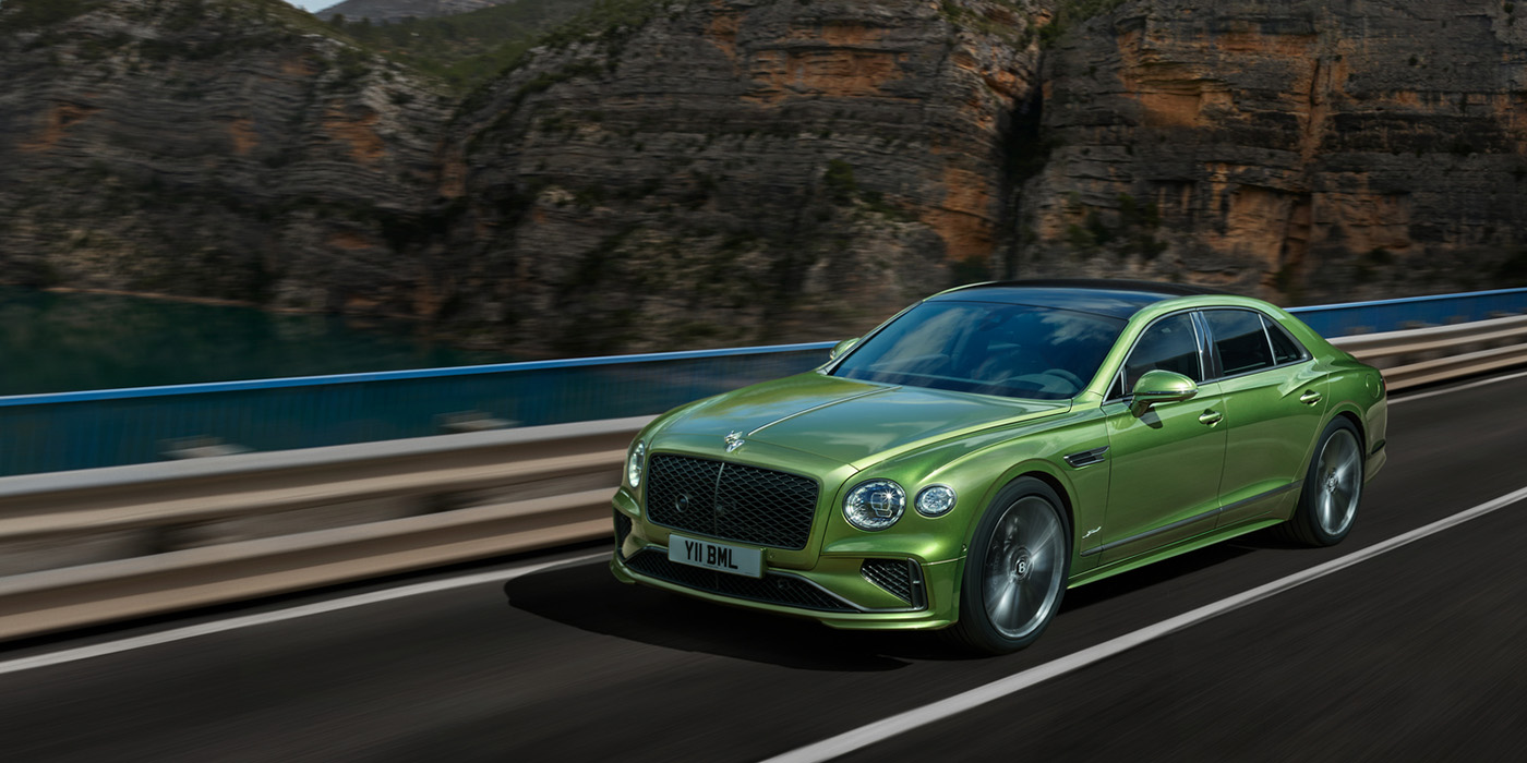 Bentley Surrey Bentley New Flying Spur Speed v8 hybrid sedan driving dynamically on a mountain road in Tourmaline Green paint