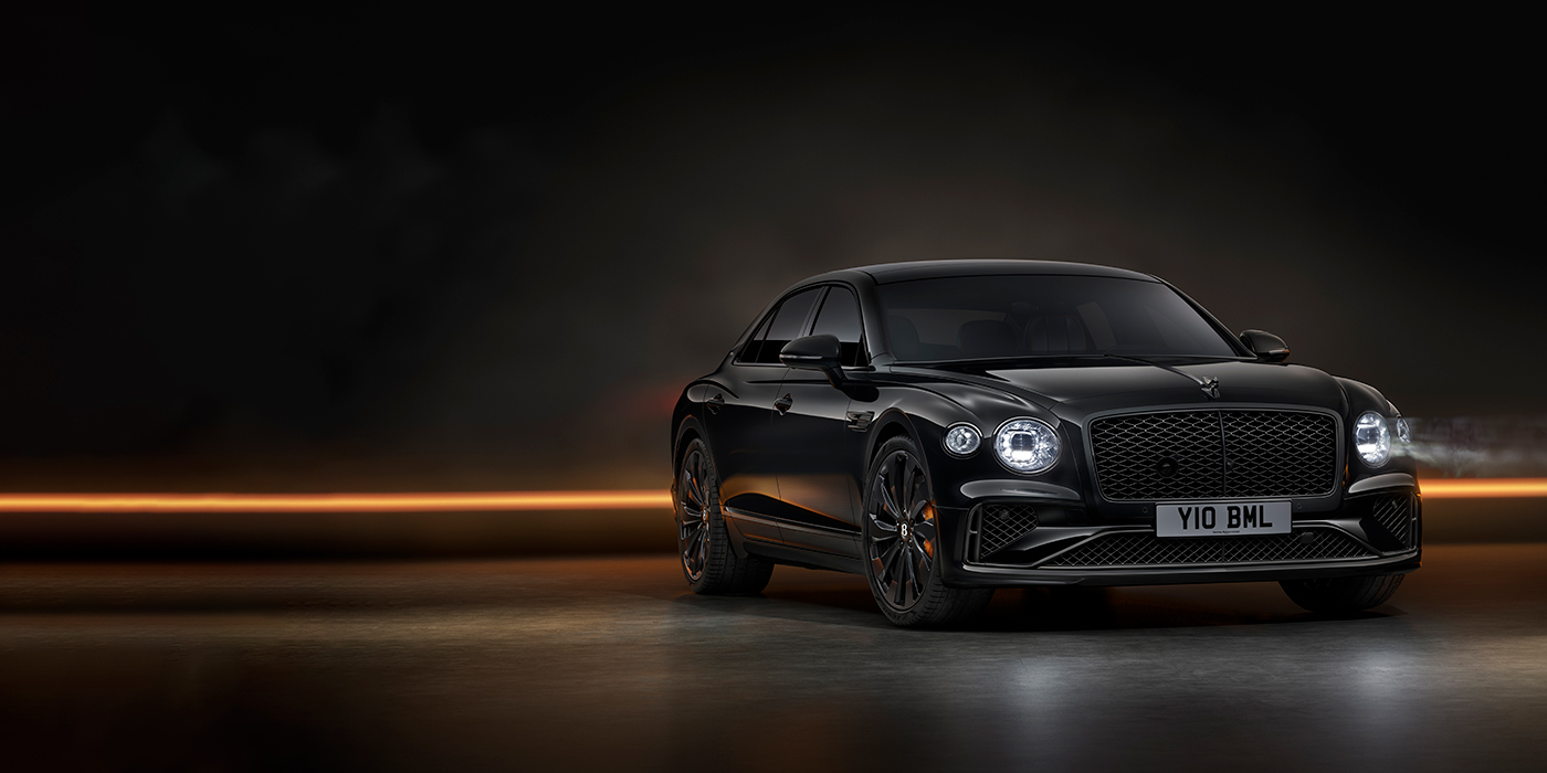 Bentley Surrey Bentley Flying Spur Black Edition sedan in Black Crystal paint against a dark grey and copper coloured background