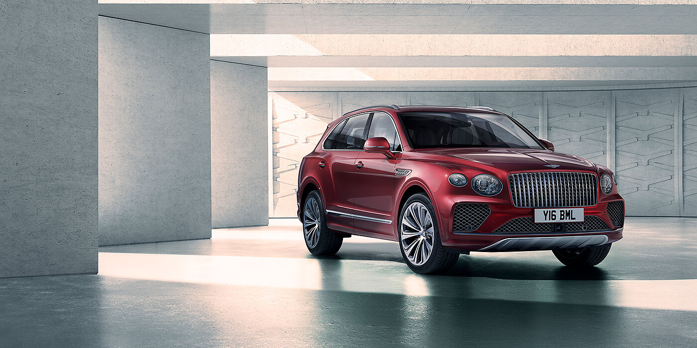 Bentley Surrey Bentley Bentayga Atelier Edition SUV in Rubino Red paint front three quarter against textured concrete wall