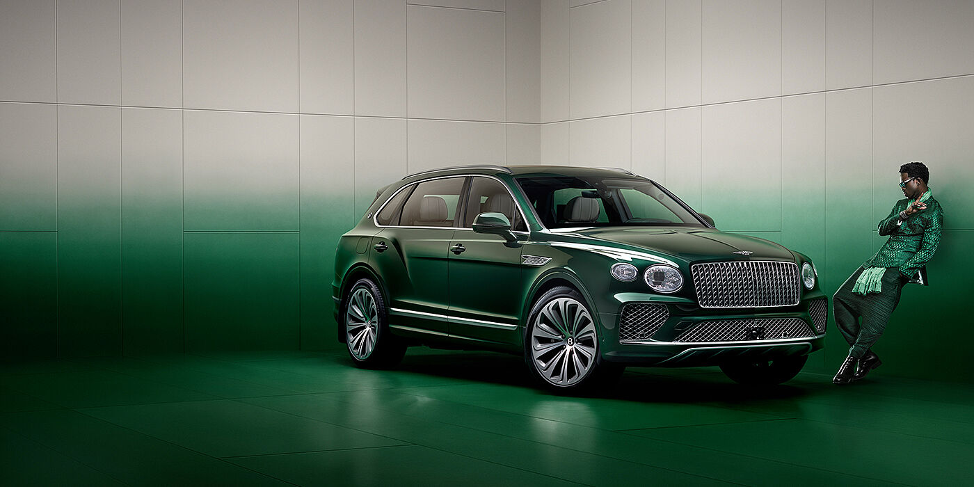 Bentley Surrey Wisdom K leans against wall next to Bentley Bentayga Extended Wheelbase Atelier Edition SUV in Light Emerald green paint