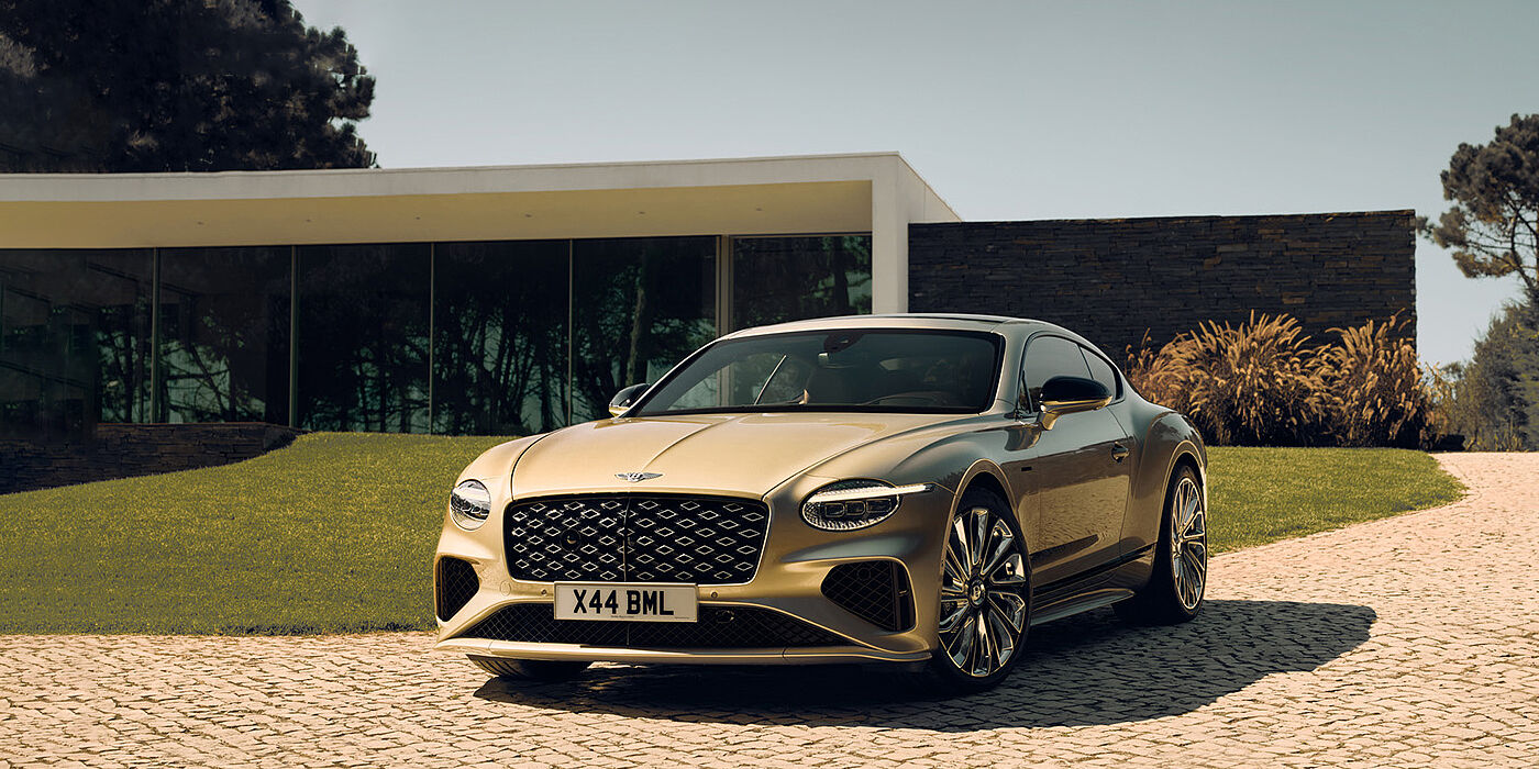 Bentley Surrey Bentley Continental GT Mulliner coupe front three quarters in Patina paint parked outside a glass fronted building with a grass lawn behind it