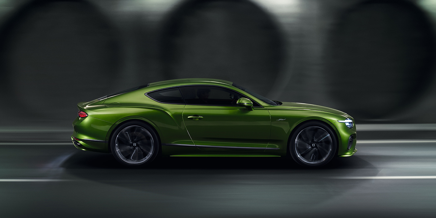 Bentley Surrey Bentley Continental GT coupe in Tourmaline Green paint driving in profile on a dark road