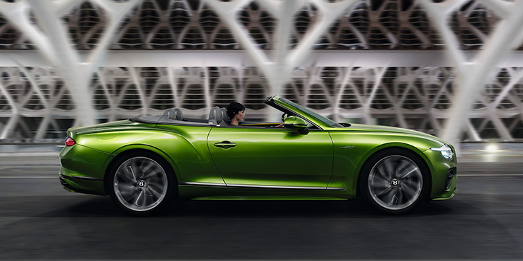 Bentley Surrey Bentley Continental GTC Speed convertible side profile in Tourmaline Green paint driving dynamically on a bridge at night