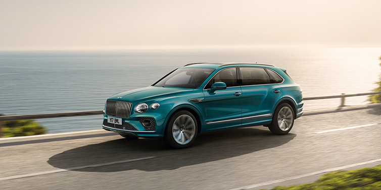 Bentley Surrey Bentley Bentayga Extended Wheelbase Azure SUV in Topaz blue paint driving dynamically by the ocean