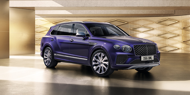 Bentley Surrey Bentley Bentayga Extended Wheelbase Mulliner SUV front three quarter in Tanzanite Purple paint with a gold patterned background