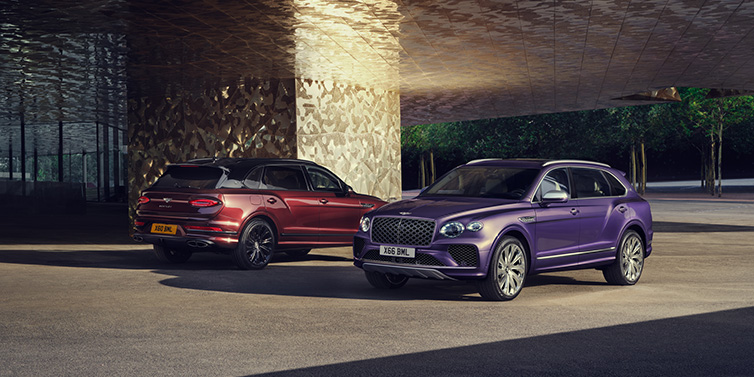 Bentley Surrey A duo of Bentley Bentayga Extended Wheelbase Mulliner SUVs parked in a city environment, with Tanzanite Purple and Cricket Ball red exterior paint