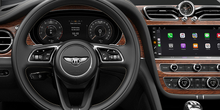 Bentley Surrey Bentley Bentayga SUV front interior detail of steering wheel and driver screens surrounded by Beluga black hide and Crown Cut Walnut veneer